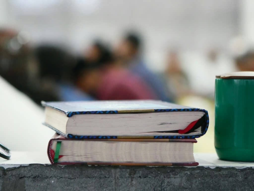 Stack of books sitting next to a coffee mug